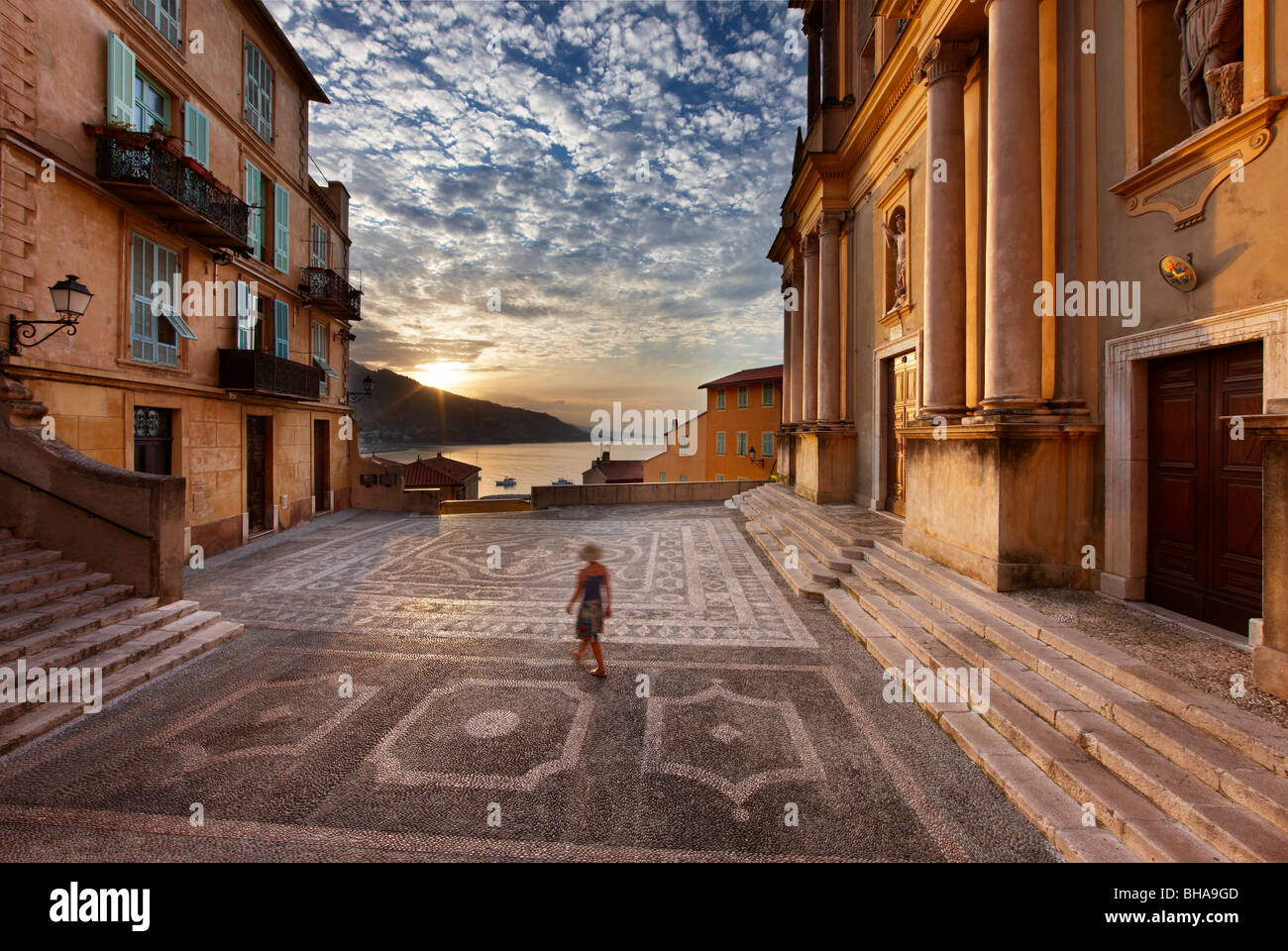 Una mujer caminando a través de Parvis St Michel al amanecer, la Ciudad Vieja, Menton, Cote d'azur, Alpes Marítimos, Provence, Francia Foto de stock