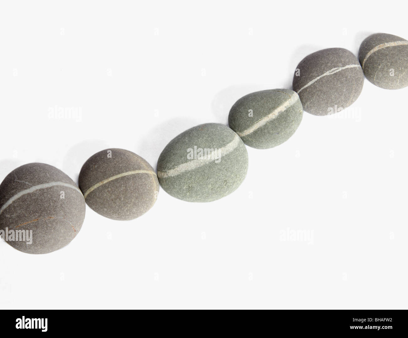 Cadena de seis guijarros creado con piedras de granito conectando una veta de cuarzo blanco en cada piedra para formar una línea continua. Foto de stock