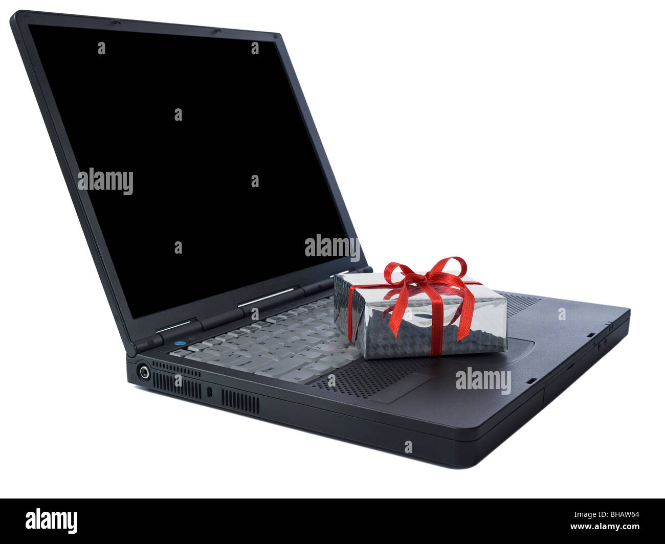 Un pequeño regalo envuelto con una cinta roja en un portátil negro aislado en blanco. Copia en negro espacio en la pantalla. Foto de stock