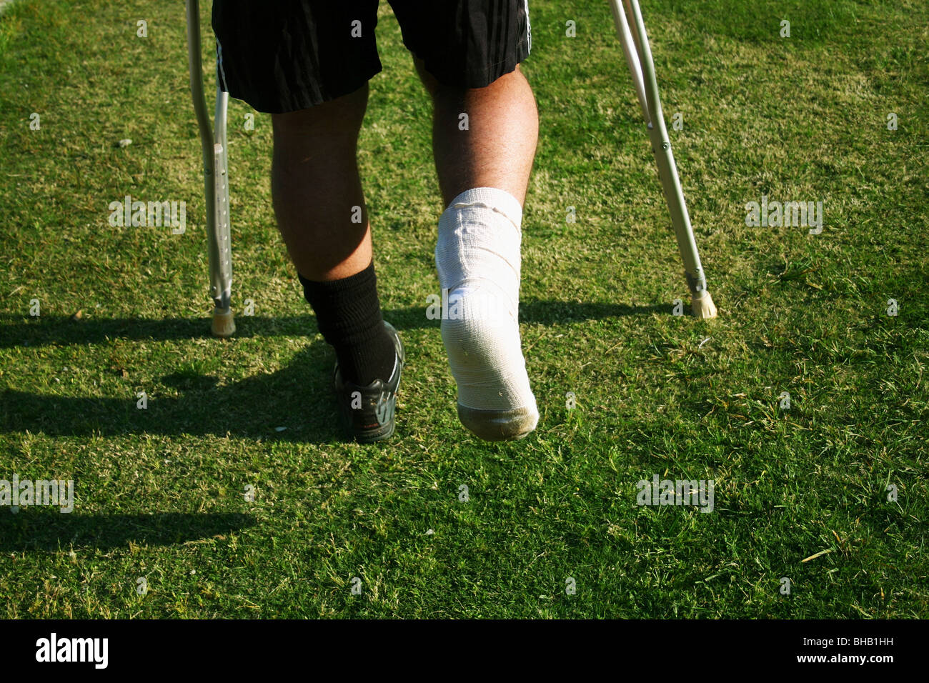 El futbolista con el tobillo grabada y vendas camina lejos del campo de  fútbol de muletas Fotografía de stock - Alamy