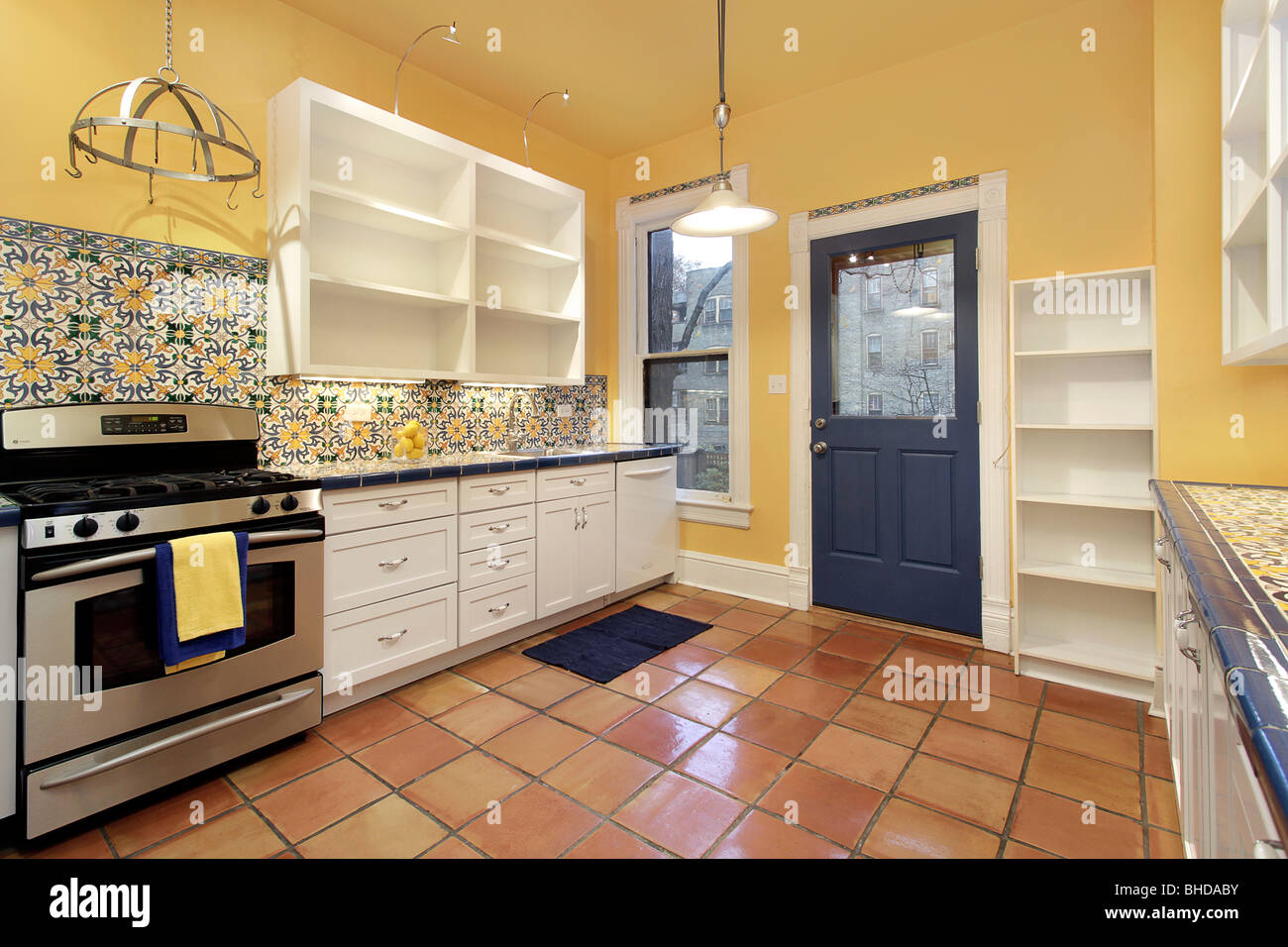 Cocina en casa suburbana con baldosas de terracota y paredes amarillas