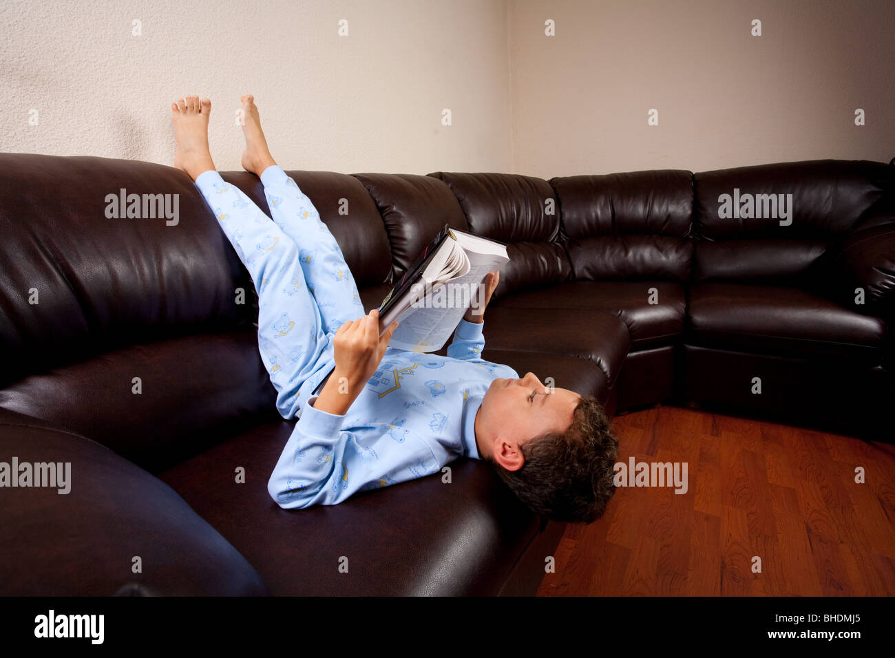 Cute colegial en pijama leyendo un libro (un diccionario), sentados en el  sofá boca abajo Fotografía de stock - Alamy