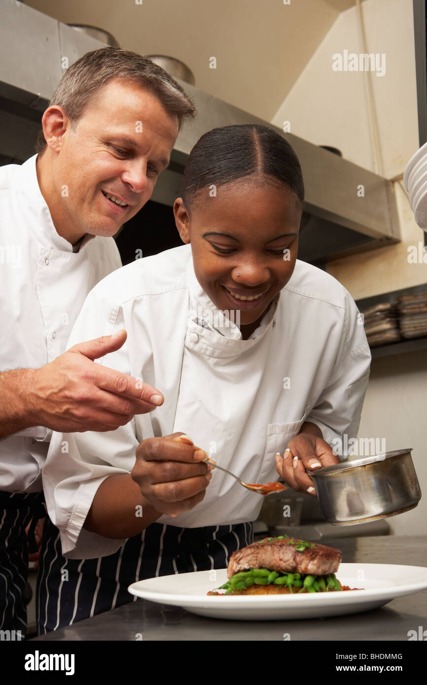 Chef instruyendo a aprendiz en cocina de restaurante Foto de stock
