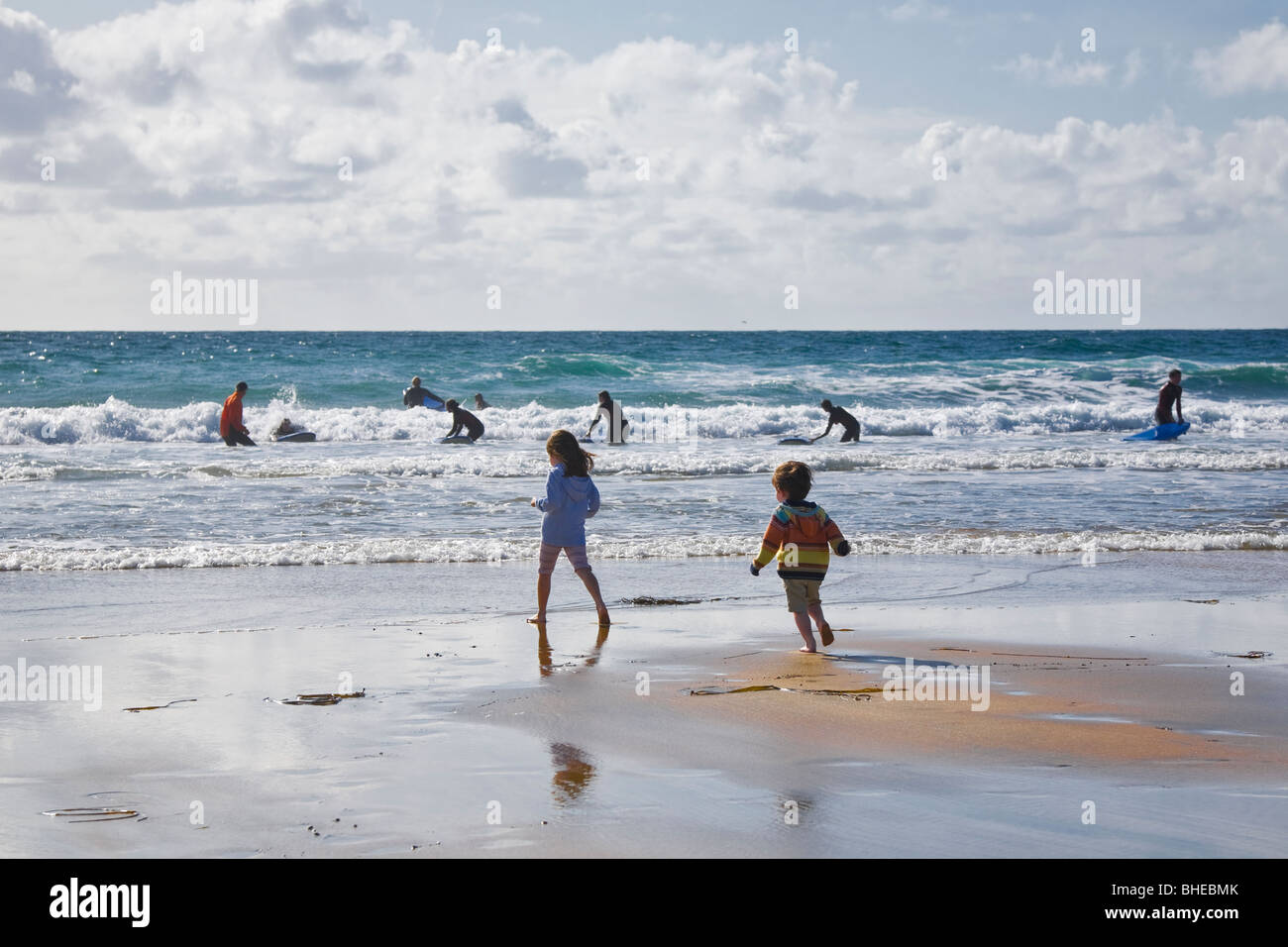 Niña y Niño viendo a los surfistas en la playa de Fanore, County Clare, Irlanda. Foto de stock