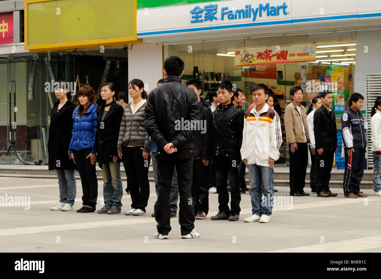 Los adolescentes chinos se alinearon fuera de una tienda local de preparación para un desfile. Foto de stock