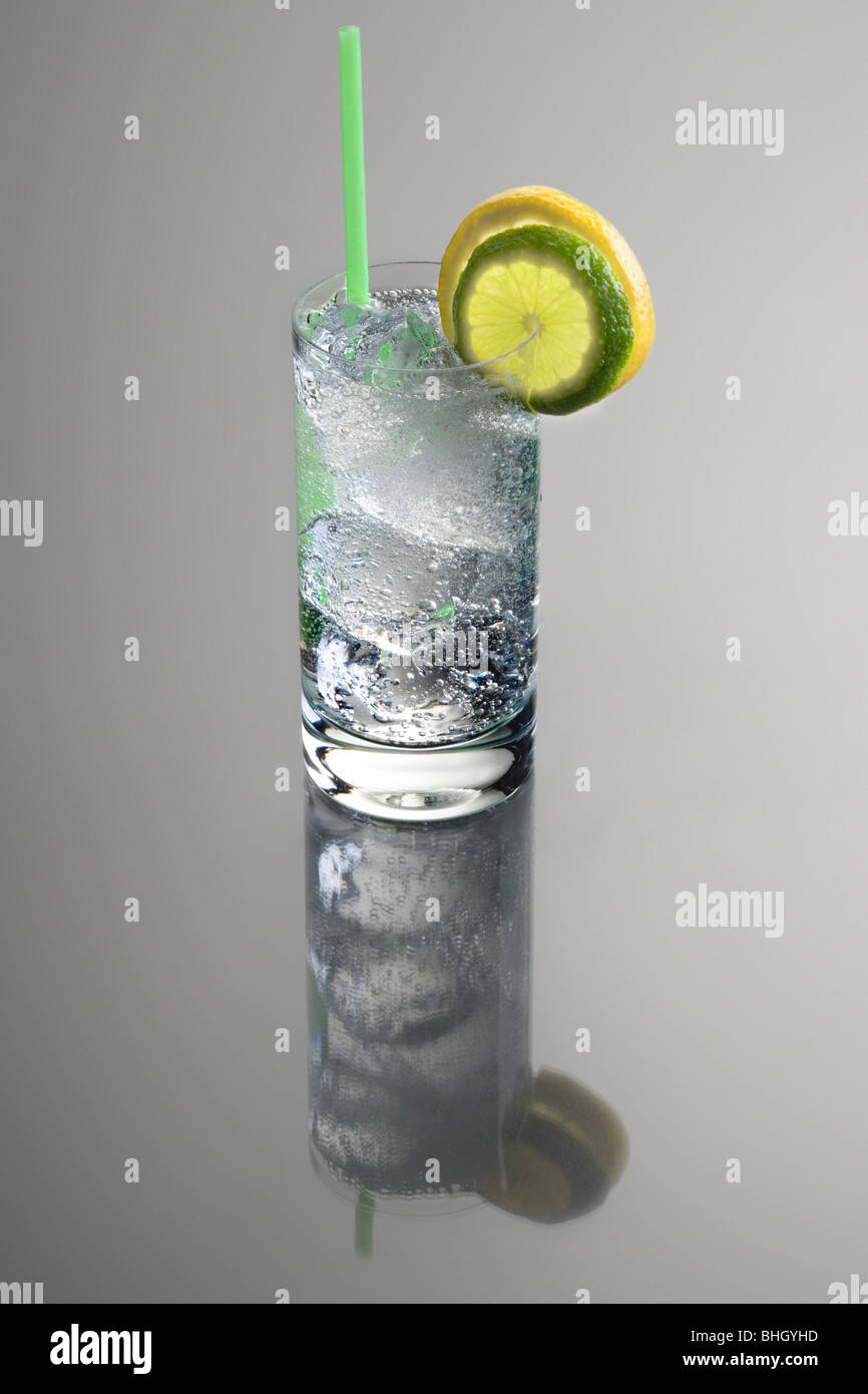 Vodka o Gin & Tonic bebida mezclada con limón y lima Guarnición cortes sobre fondo gris con reflexión Foto de stock