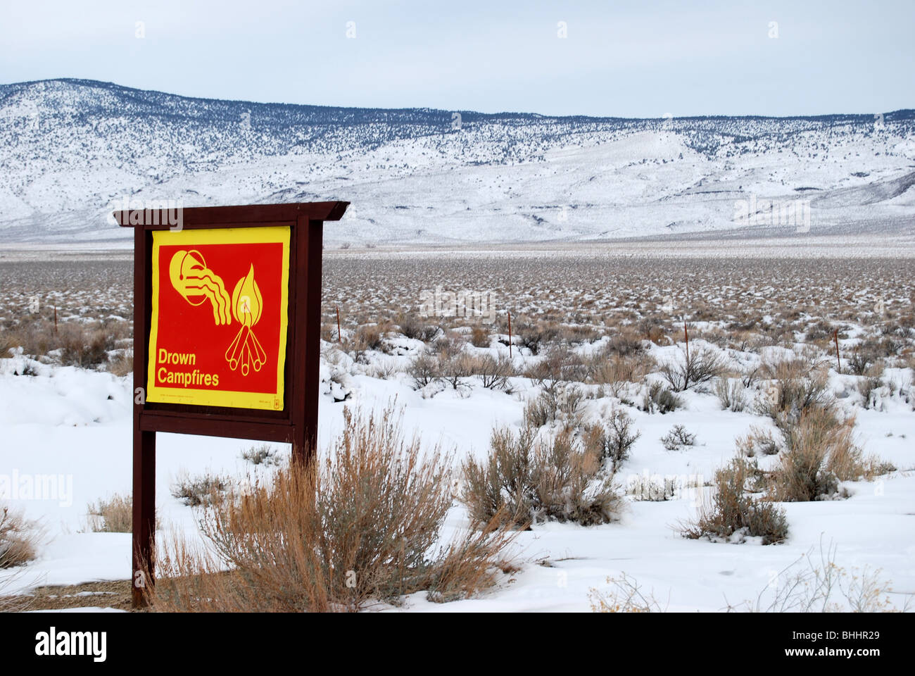 Una fogata dowse firmar en la parte oriental de la sierra de California, EE.UU. frente a un hermoso paisaje cubierto de nieve Foto de stock
