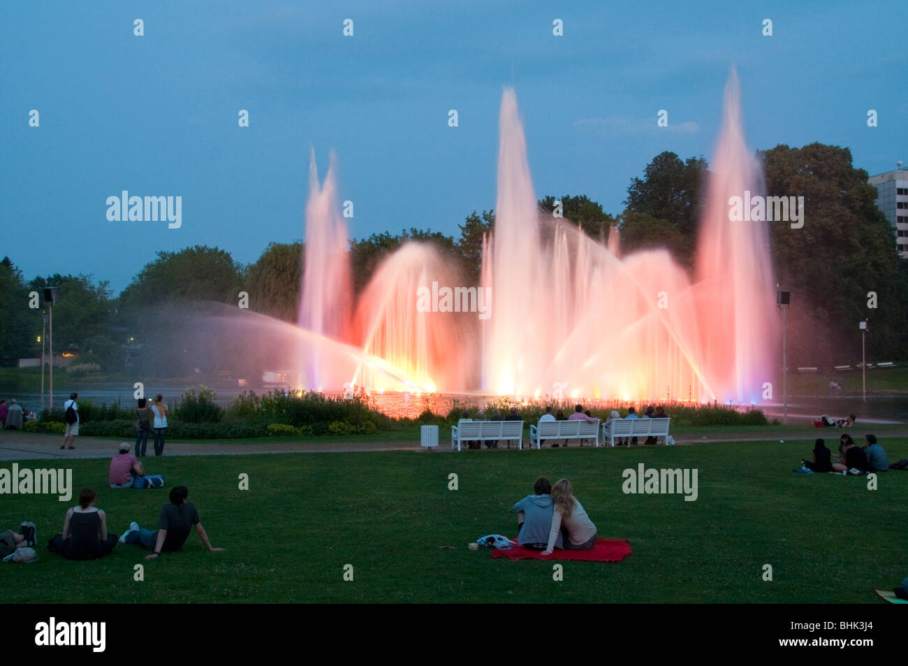 Planten un Blomen, Wasserspiele bei Daemmerung, Menschen auf Wiese, Hamburgo, Alemania Foto de stock