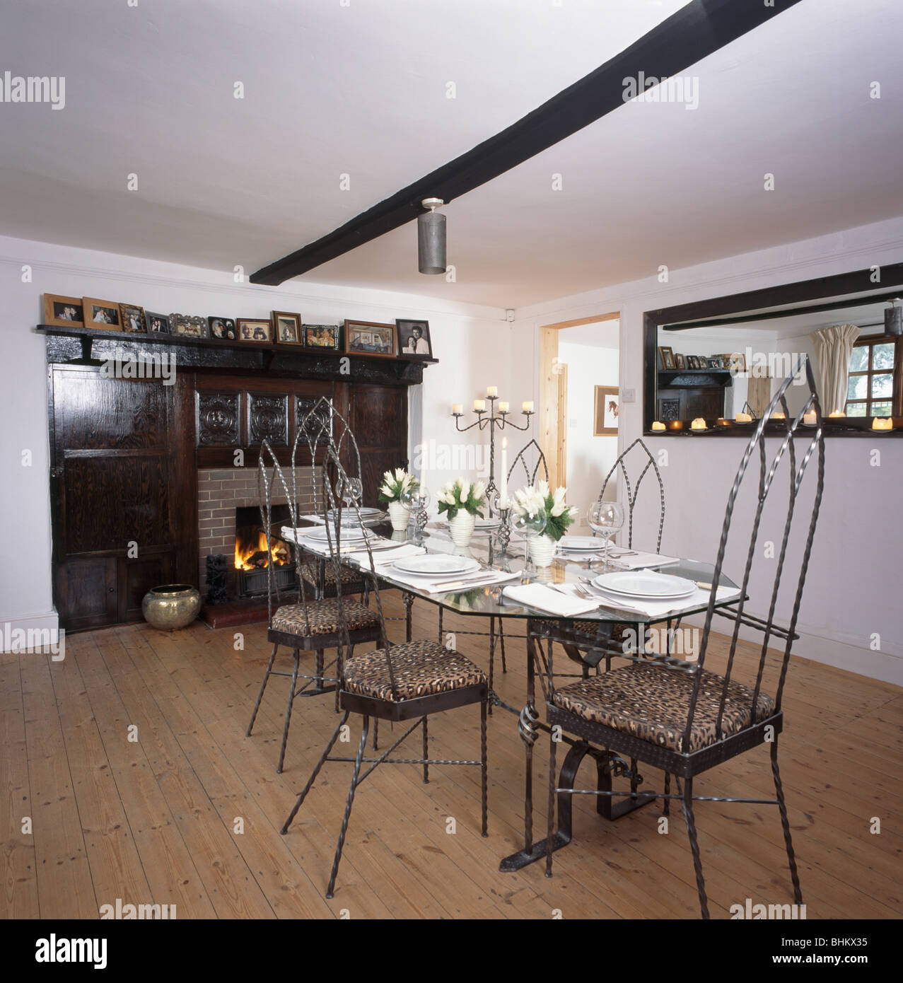 De estilo gótico, Metal sillas y mesa con vajilla blanca en blanco país  comedor con pisos de madera y el fuego en la chimenea Fotografía de stock -  Alamy