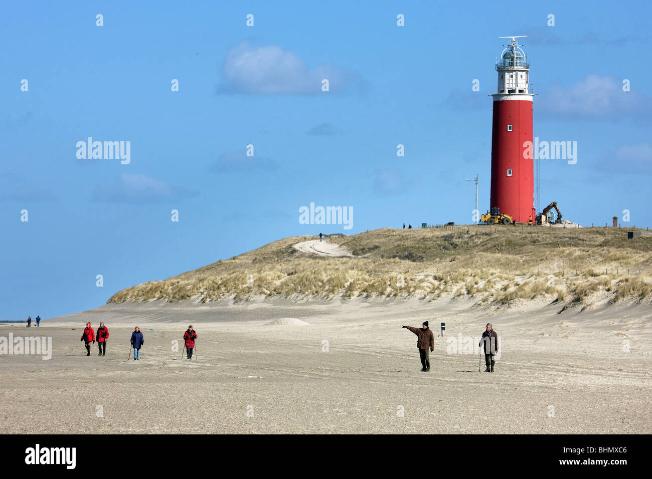 Caminantes en la playa y faro de Cocksdorp, Texel, en los Países Bajos Foto de stock