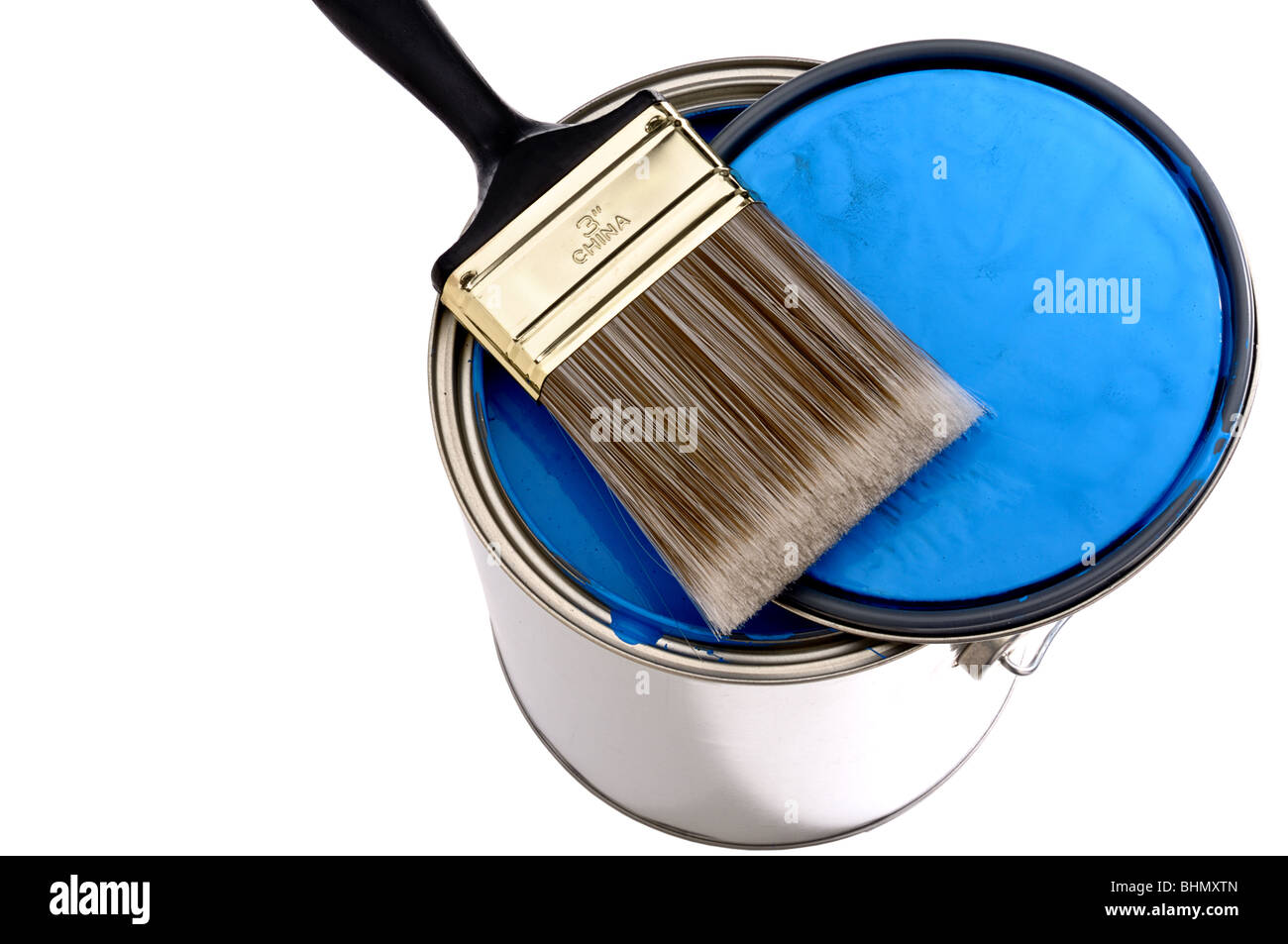 El cepillo de la pintura y la tapa sobre la parte superior de una lata de pintura azul Foto de stock