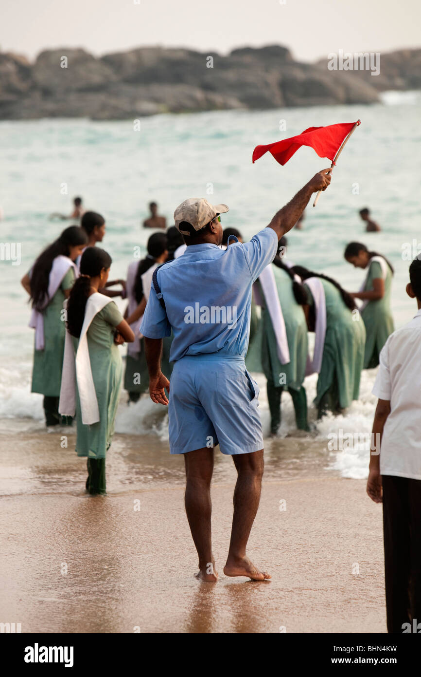 India, Kerala, Kovalam, Hawah (Eve) Playa, socorrista ondeando la bandera roja a los bañistas en peligro Foto de stock