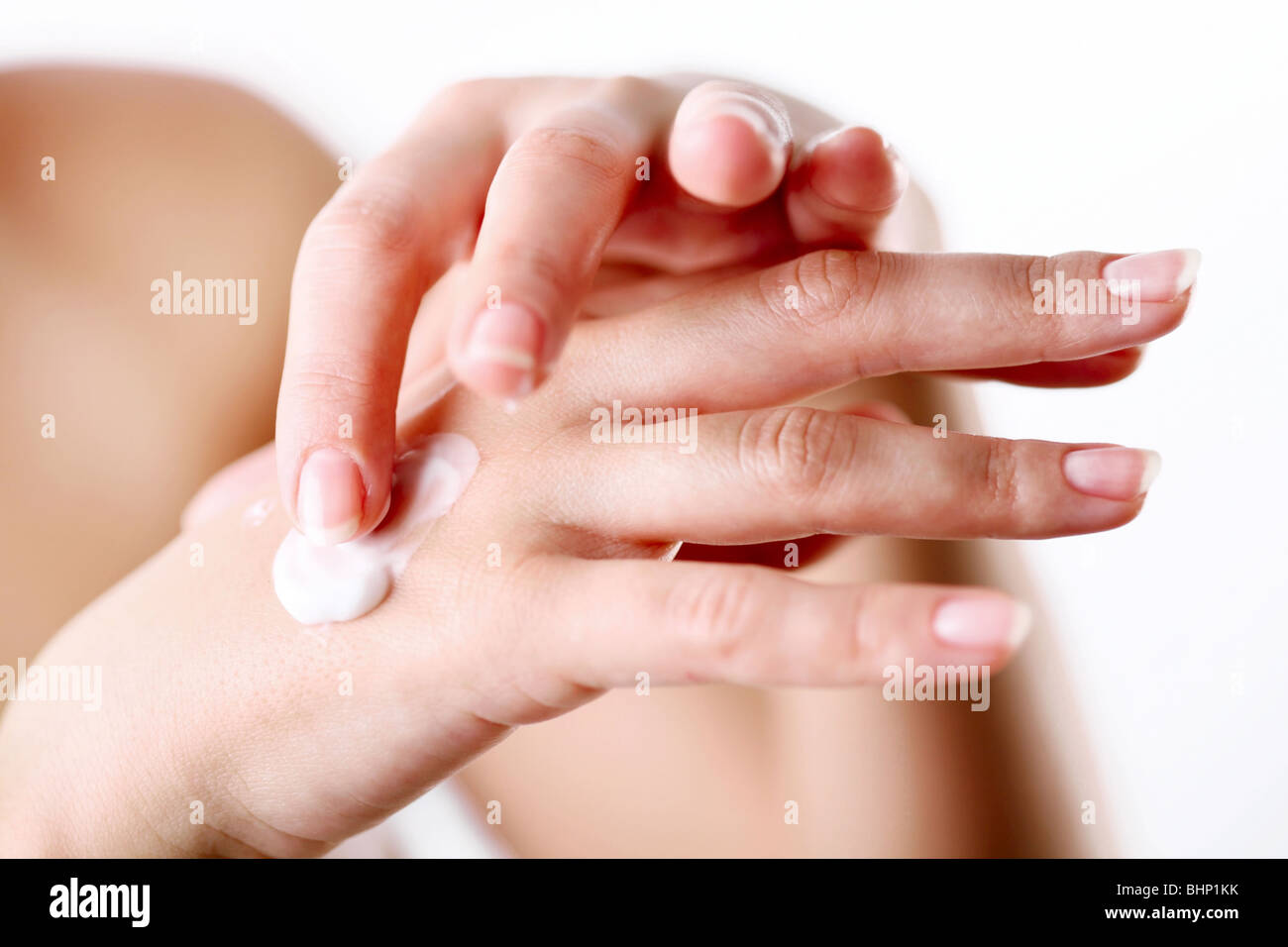 Mujer joven se preocupa por sus manos, aplicar crema sobre ellos. Foto de stock