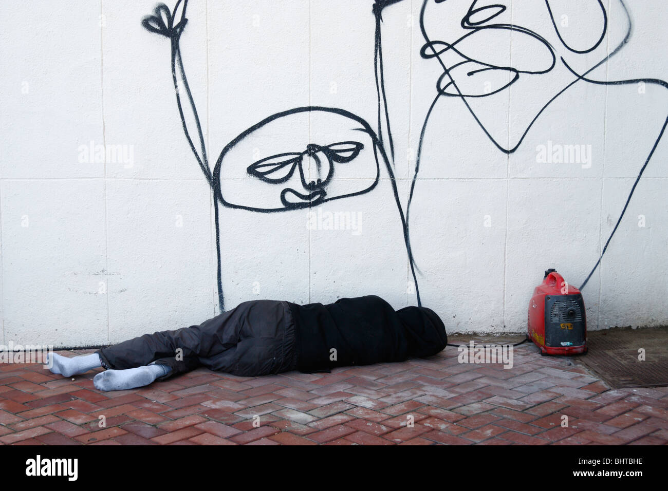 Adolescente sin zapatos durmiendo en la calle con ruidoso generador pequeño  junto a su cabeza Fotografía de stock - Alamy