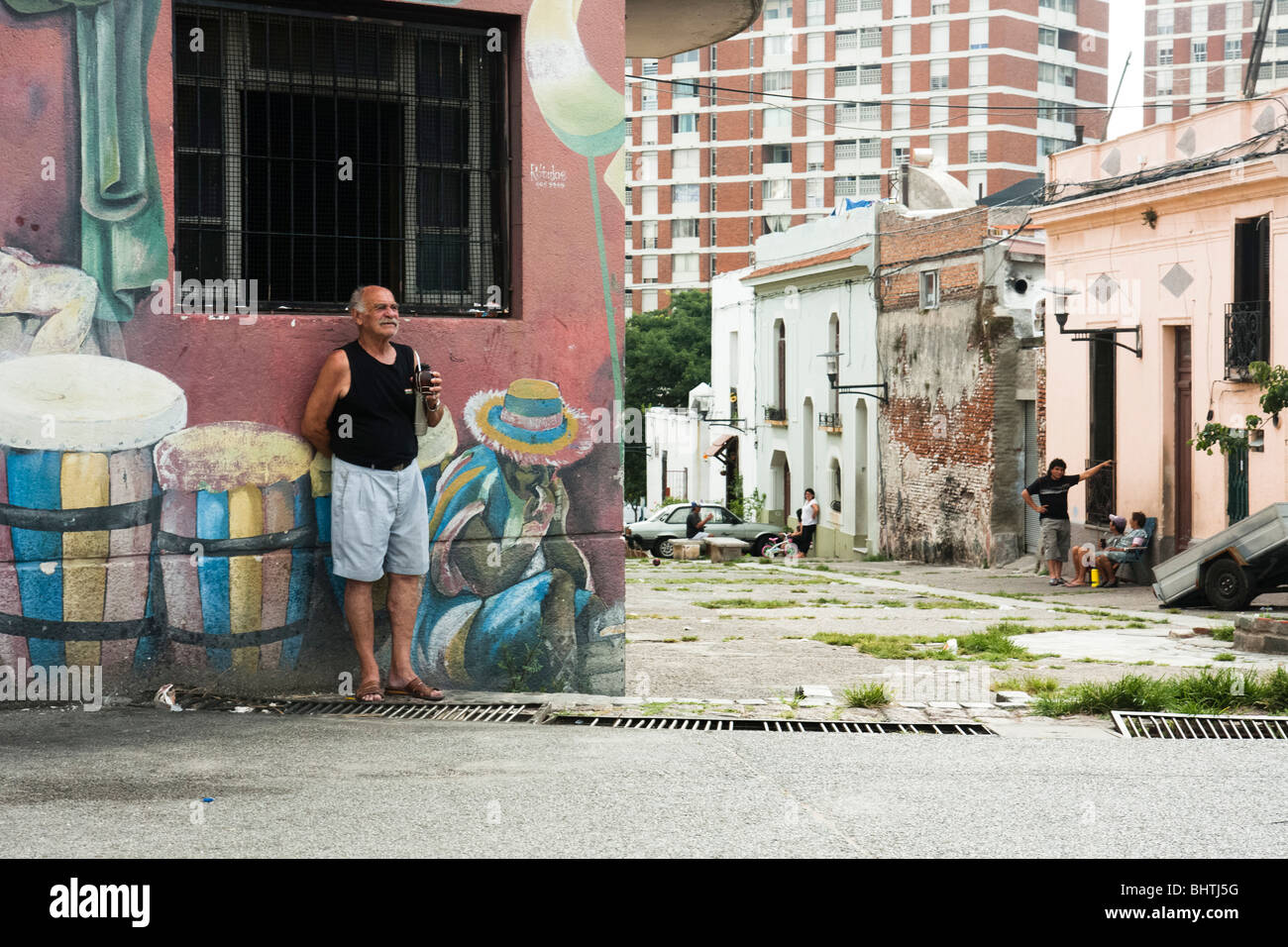 Un hombre sorbos mate mientras ve un tambor práctica sobre la esquina de Curuguaty y Carlos Gardel en Montevideo, Uruguay. Foto de stock