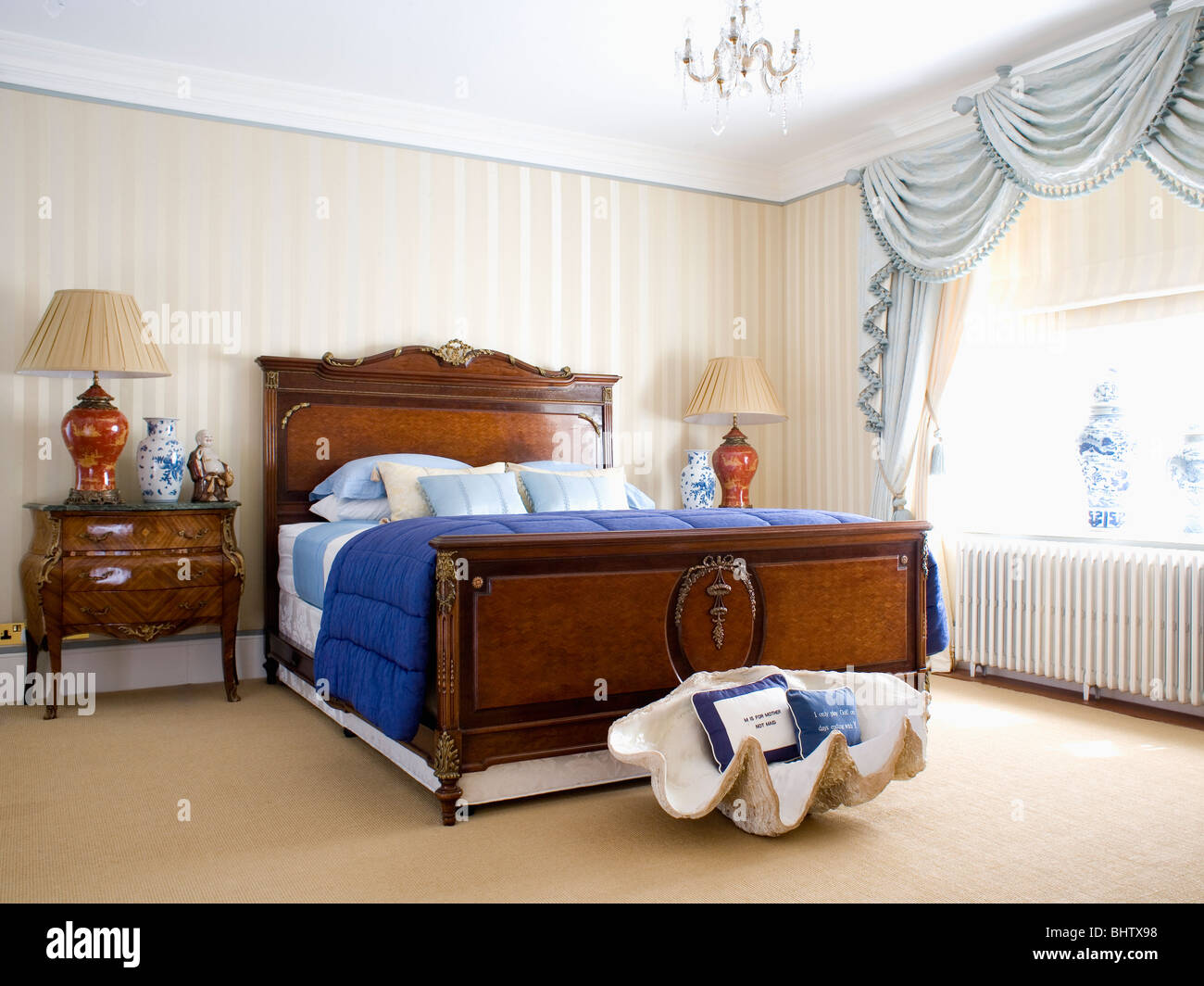 Concha grande debajo de la caoba cama con edredón azul en el dormitorio con papel  tapiz a rayas de color beige y azul pálido swagged cortinas Fotografía de  stock - Alamy