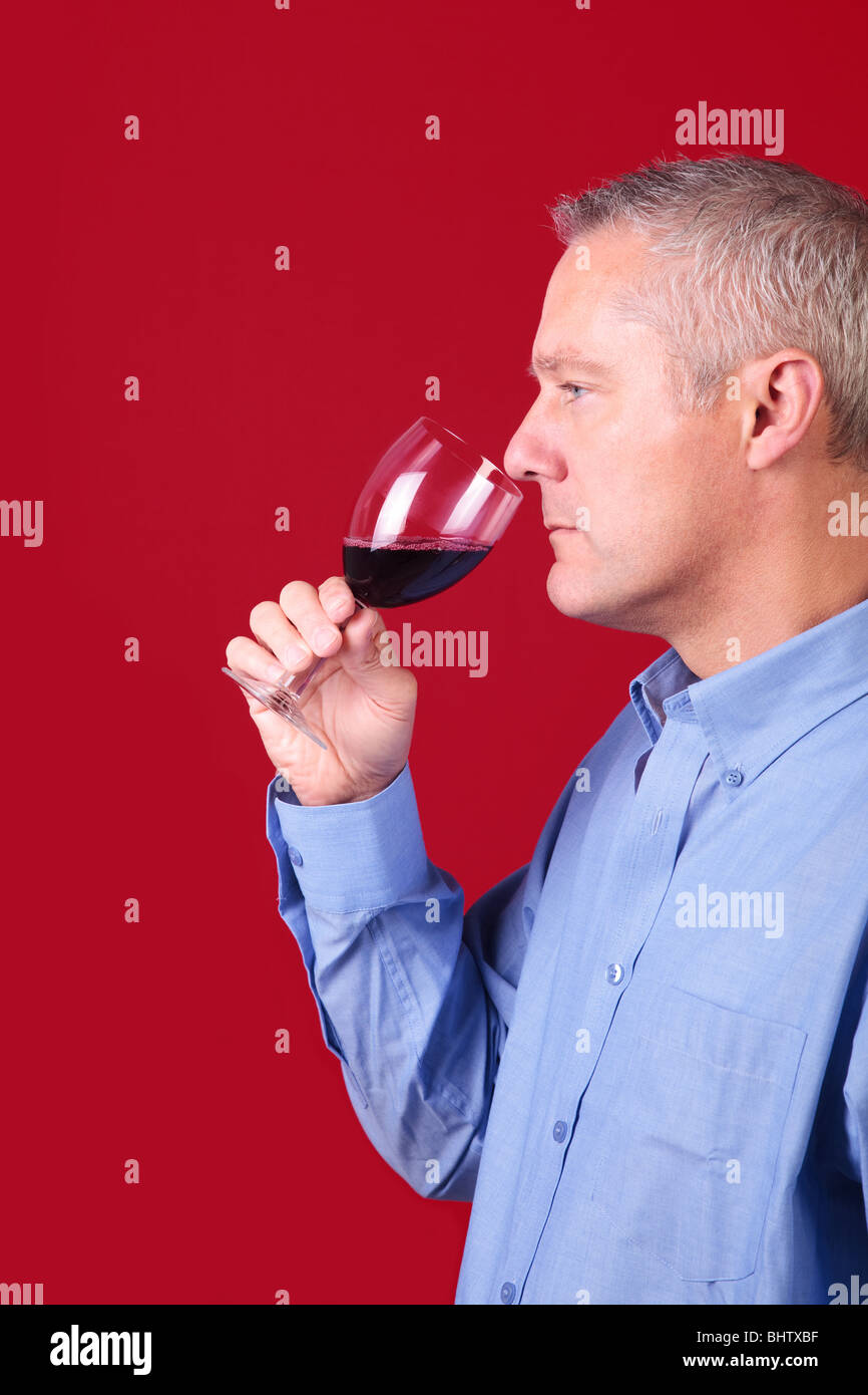 Hombre oler un vaso de vino tinto para comprobar su aroma Foto de stock