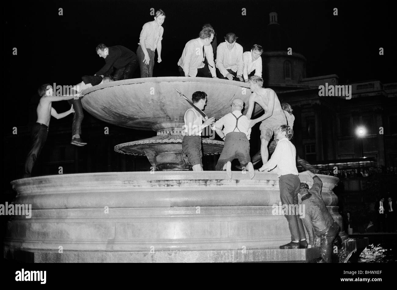 Torneo de la Copa Mundial de 1966 en Inglaterra. Inglaterra fans celebran en las fuentes de Trafalgar Square en Londres a la 1am en la noche Foto de stock