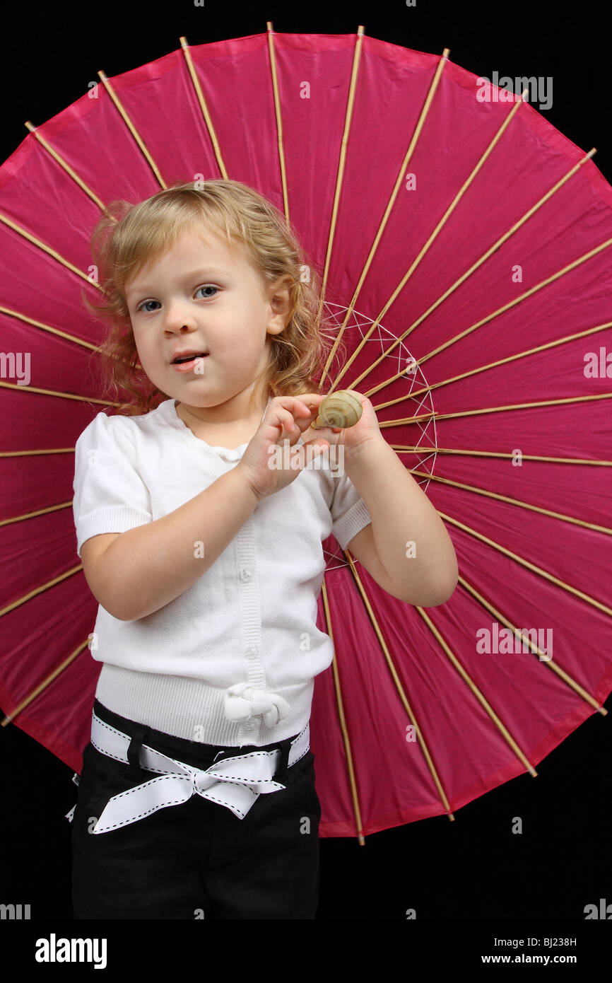 Un de 3 años rubia niña, vestida con un pantalón top y sosteniendo un rosa caliente Fotografía de stock - Alamy
