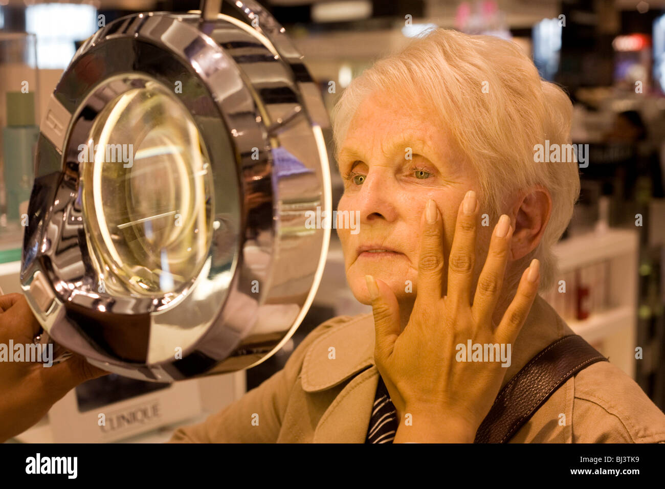 Anciana recibe una consulta de esteticista profesional en la Clinique Bar en World Duty Free en el aeropuerto de Heathrow Foto de stock