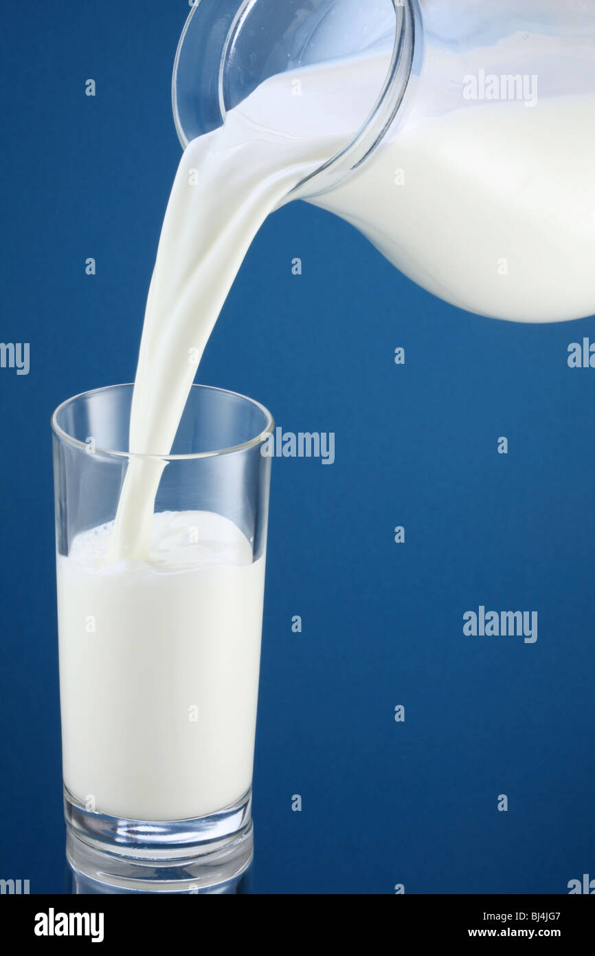 Colado de la leche de una jarra en un vaso Foto de stock