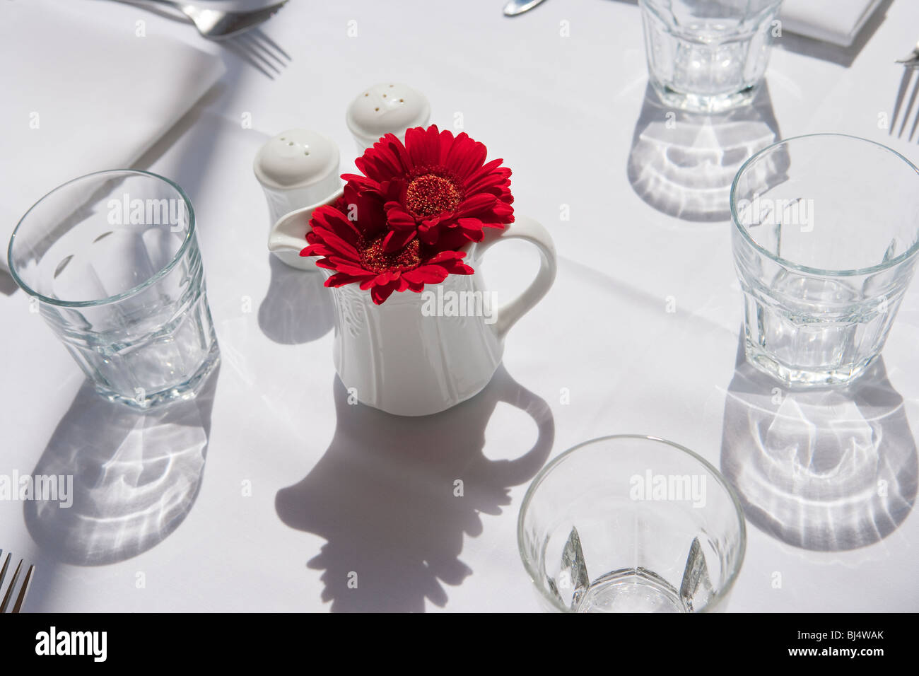 Ajuste de la tabla solo lugar decorado con flores rojas Foto de stock