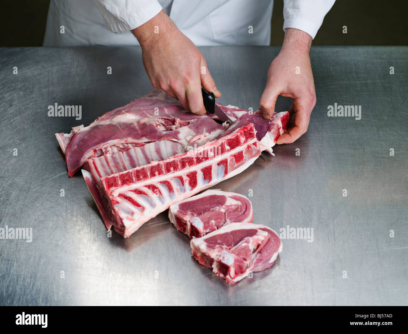 Un carnicero cortando una carne Foto de stock