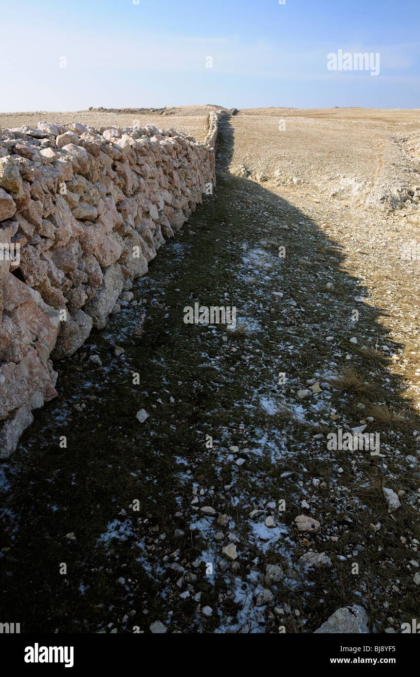 Karst yermo paisaje con muro de piedra seca en la montaña Baška Obzova (cerca), sland Krk, Croacia Foto de stock