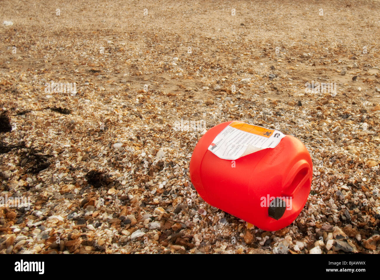 Plástico rojo puede que contengan residuos tóxicos arrastrados hasta una playa Foto de stock