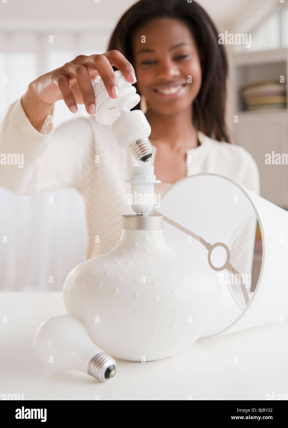 Mujer de raza mixta poniendo en la lámpara lámpara CFL Foto de stock