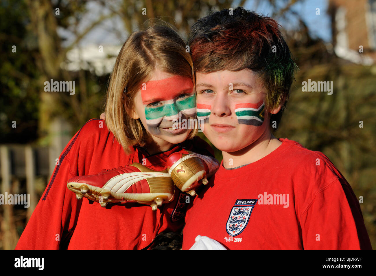 Los hinchas de fútbol joven chico y chica de Inglaterra camisas vestidos de rojo con el rostro pintado de caras en los colores de la bandera nacional de ZA Foto de stock