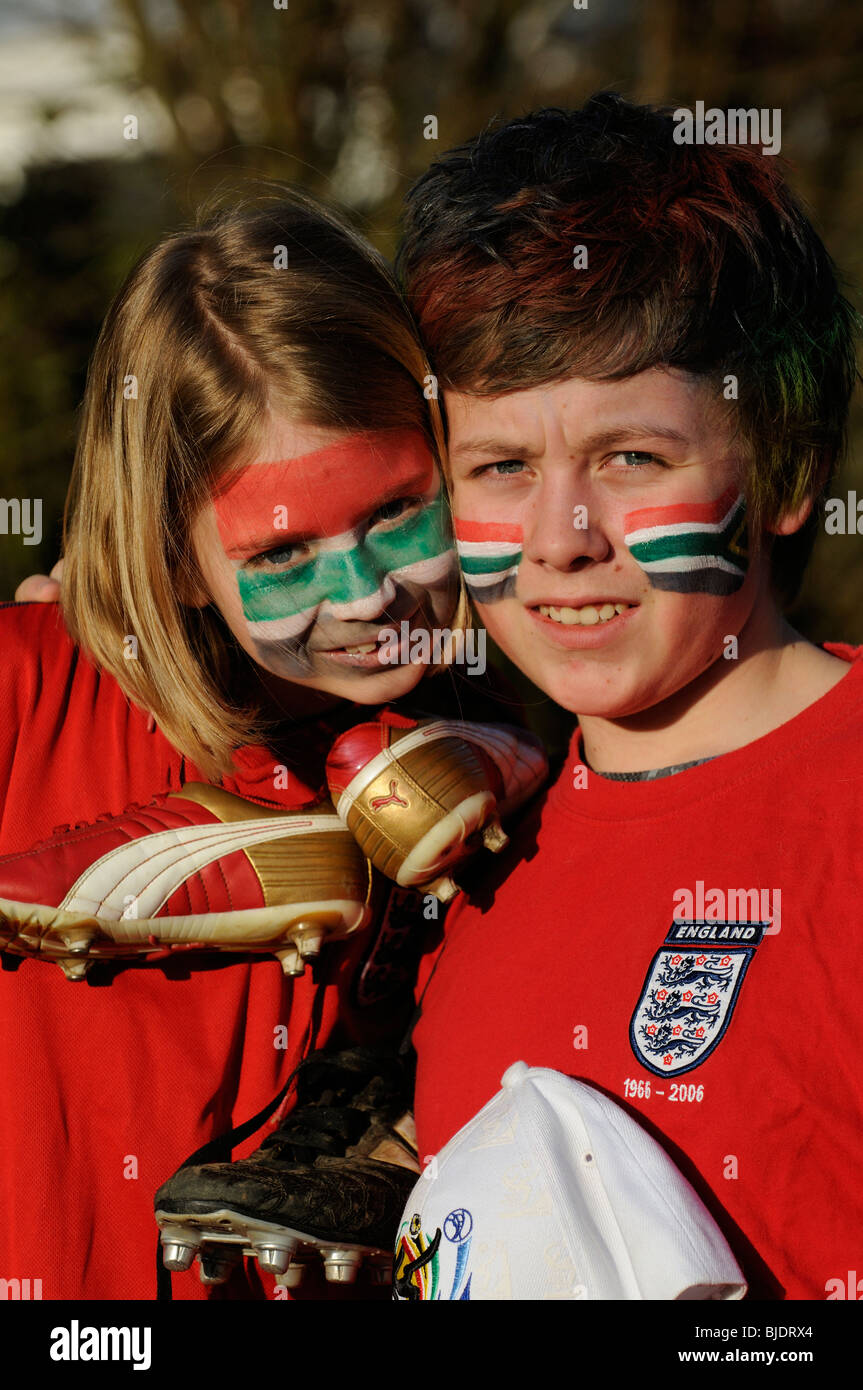 Los hinchas de fútbol joven chico y chica de Inglaterra camisas vestidos de rojo con el rostro pintado de caras en los colores de la bandera nacional del Sur Foto de stock