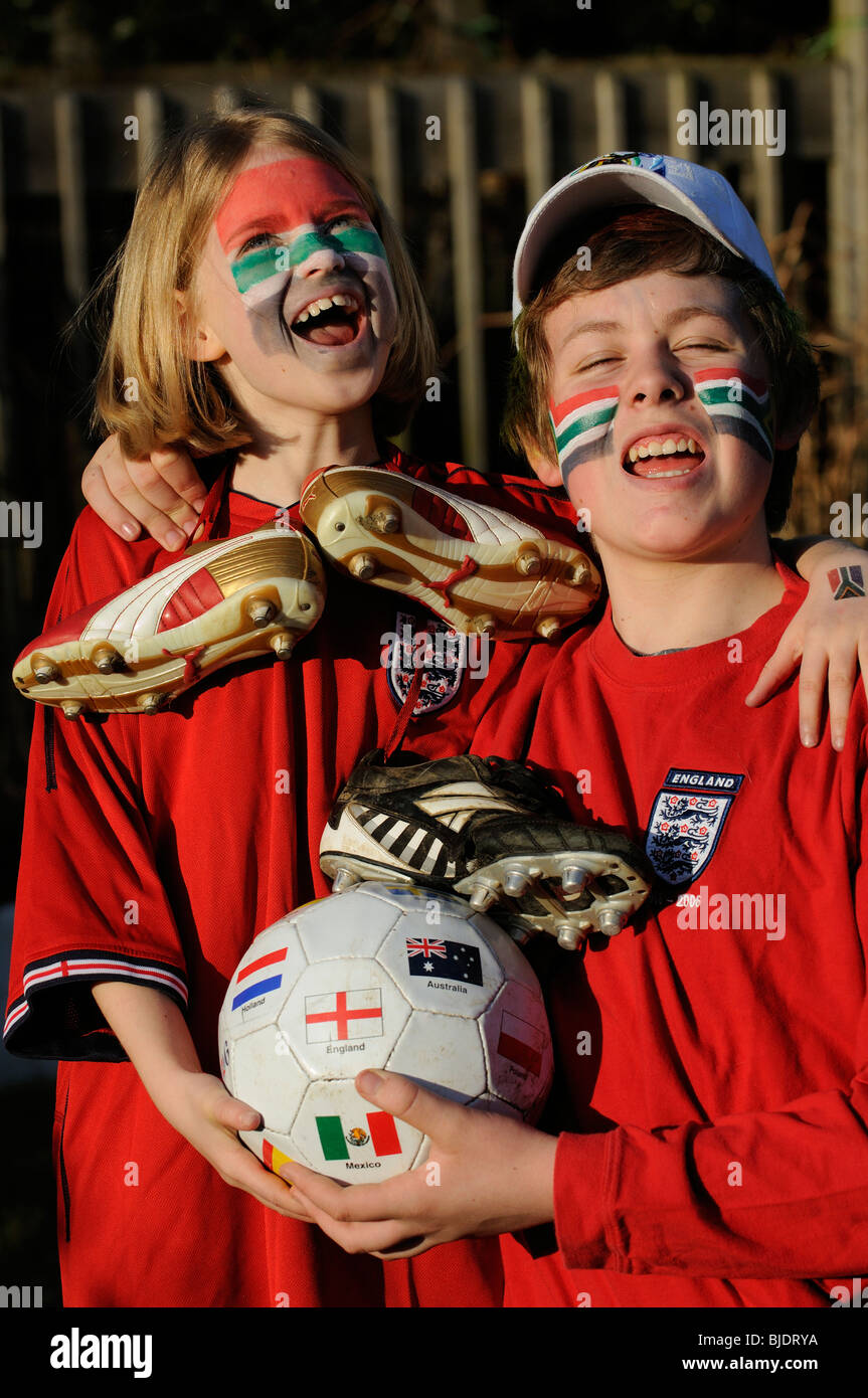 Los hinchas de fútbol joven chico y chica de Inglaterra camisas vestidos de rojo con el rostro pintado de caras en los colores de la bandera de Sudáfrica Foto de stock
