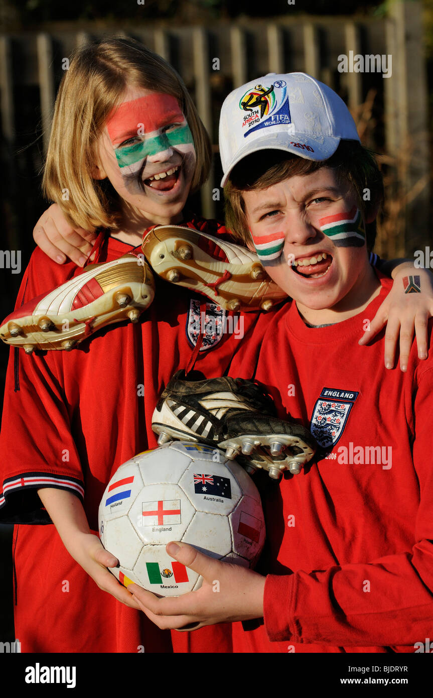 Los hinchas de fútbol joven chico y chica de Inglaterra camisas vestidos de rojo con el rostro pintado de caras en los colores de la bandera de Sudáfrica Foto de stock