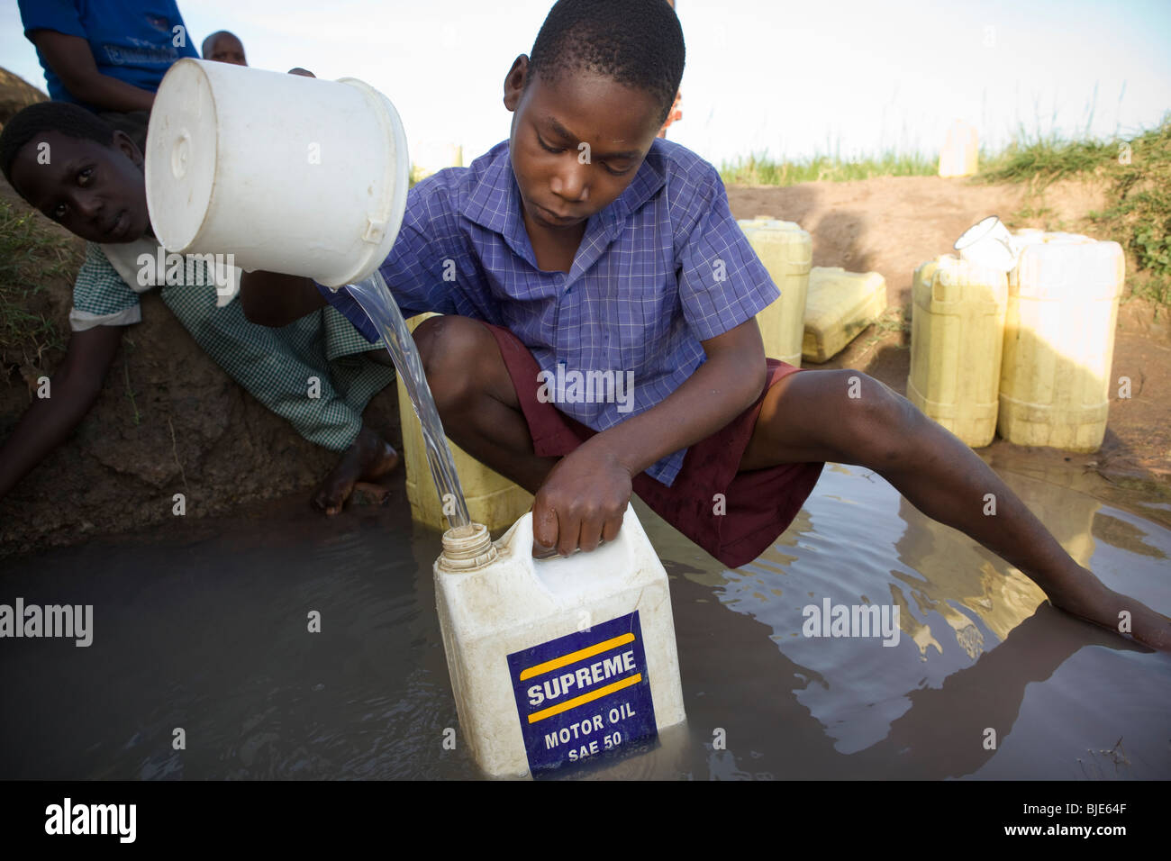 Los niños extraen agua de un abrevadero, en el distrito de Amuria, Uganda, África Oriental. Foto de stock