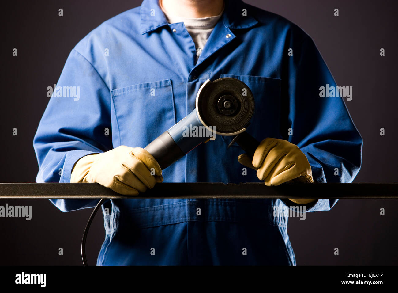 Hombre en overoles azules con una amoladora de potencia Foto de stock