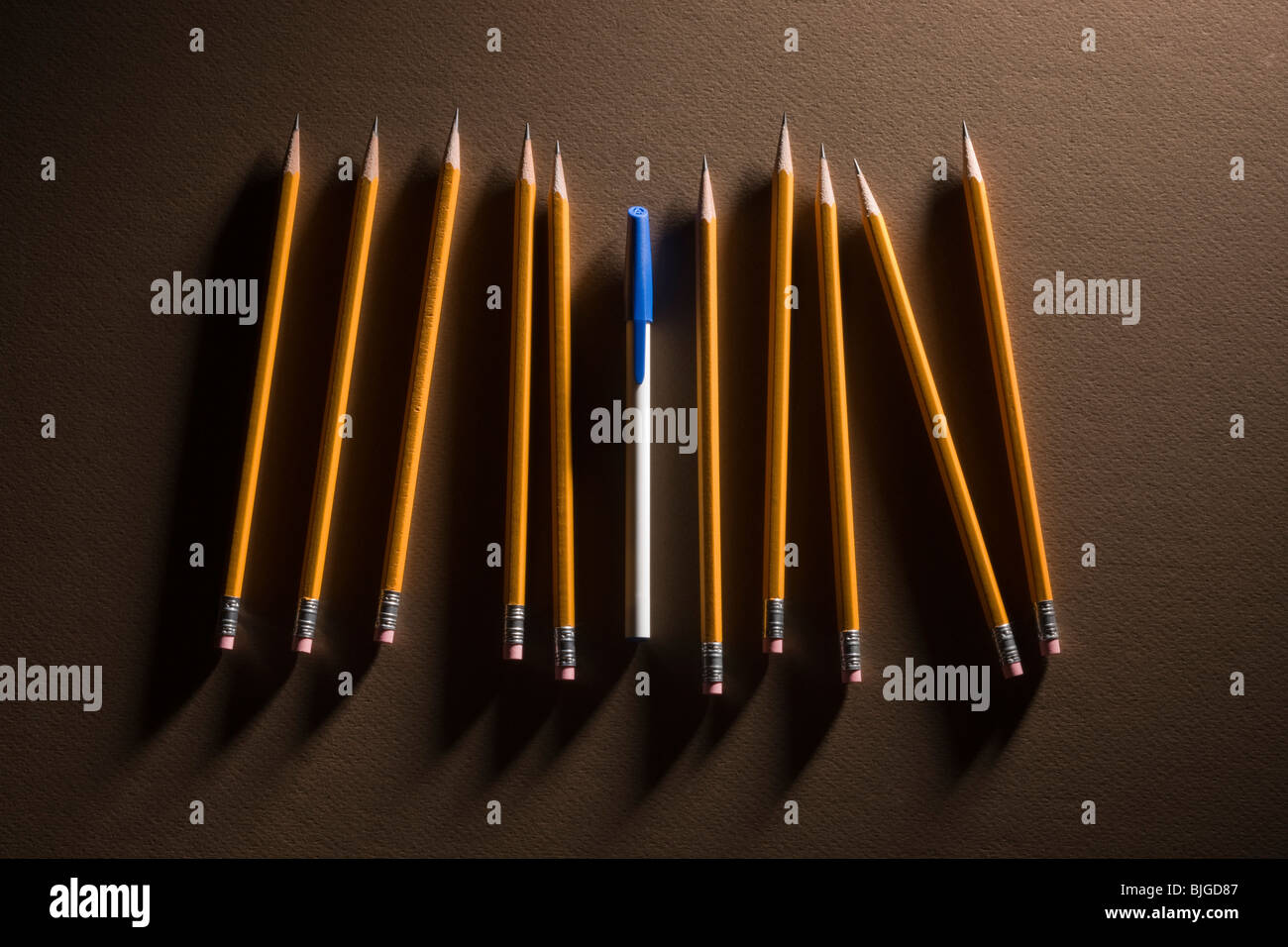 Una pluma entre muchos lápices Foto de stock