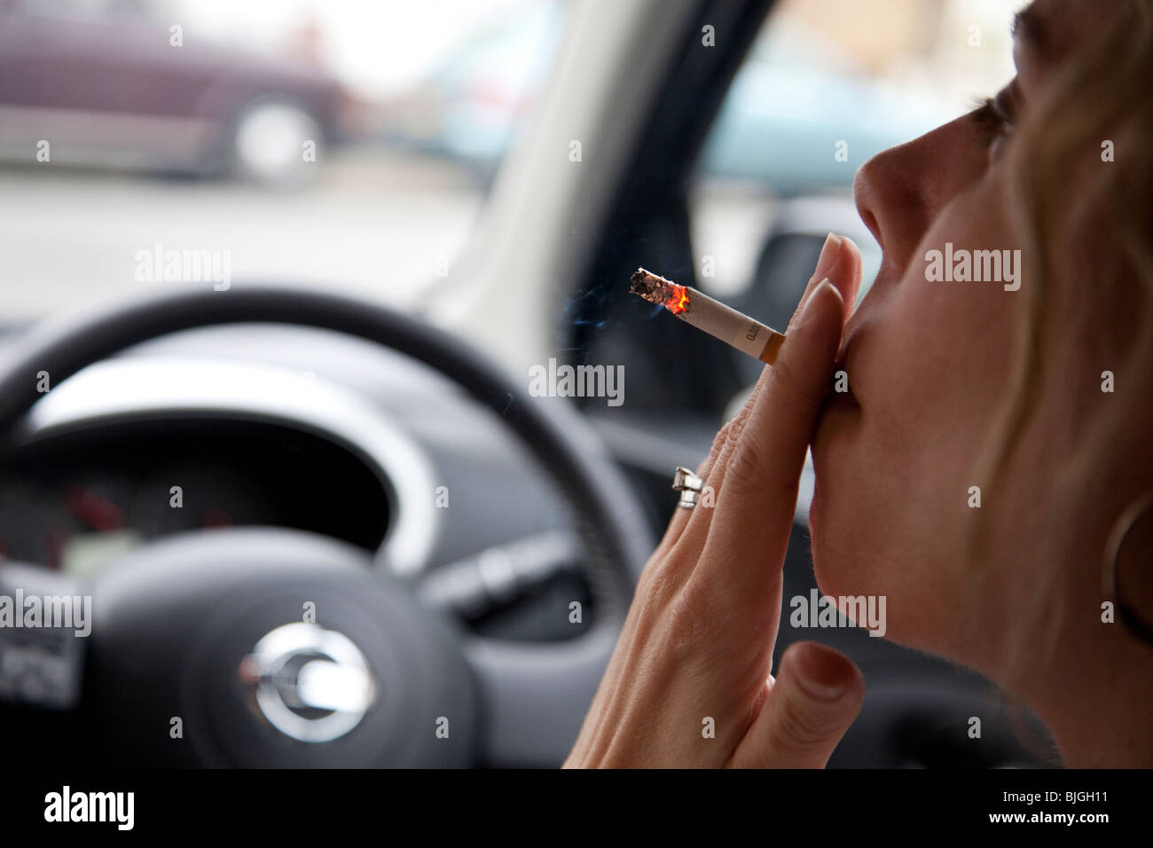 Mujer de fumar cigarrillo en coche. Los médicos en el Reino Unido están pidiendo una prohibición de fumar en los coches. Foto de stock