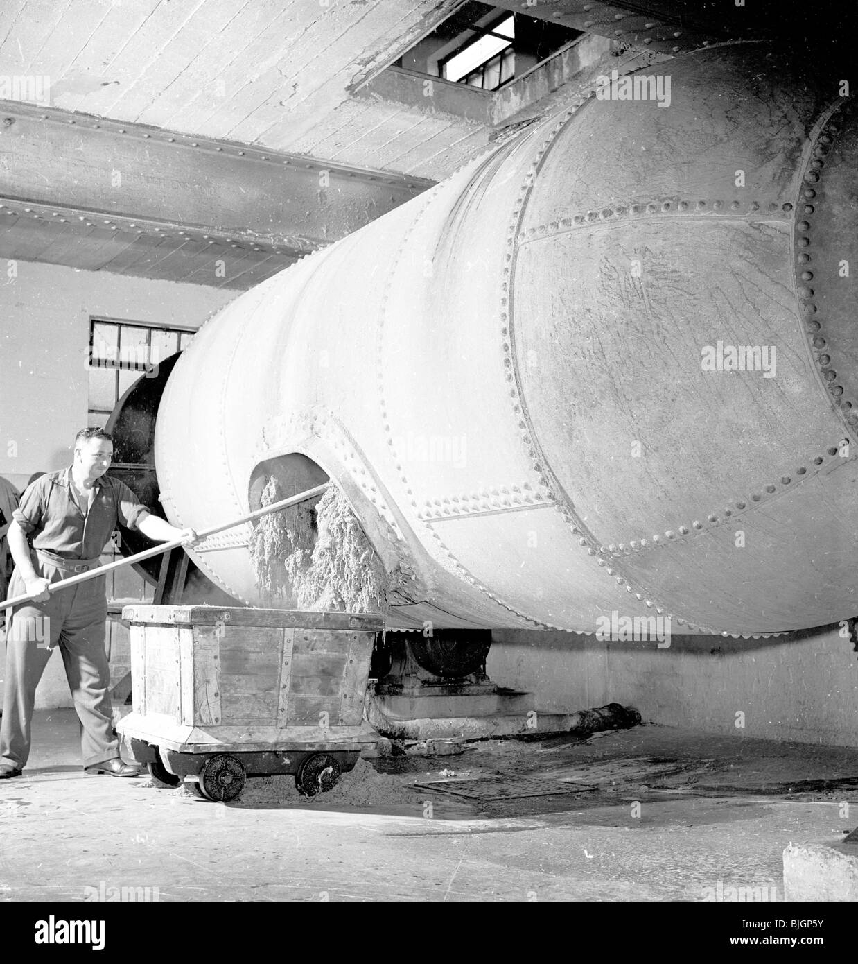 Trabajador masculino en monos de pulpa de carga en una máquina que hace el  papel, Inglaterra, 1950. Brittain La fábrica de papel Fotografía de stock -  Alamy