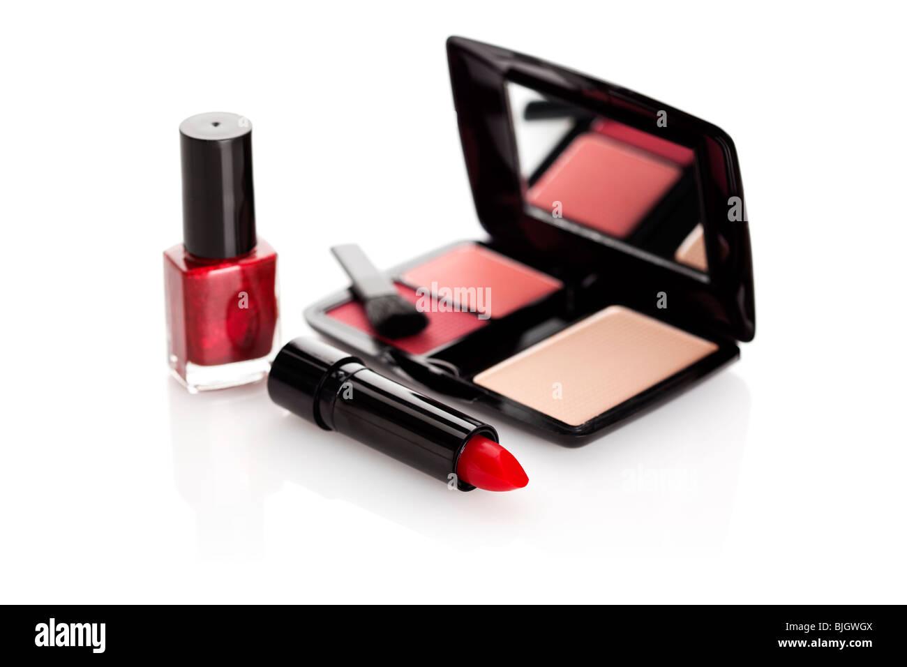Lápiz labial rojo, laca de uñas y caso con rouge y maquillaje sobre fondo blanco. Foto de stock