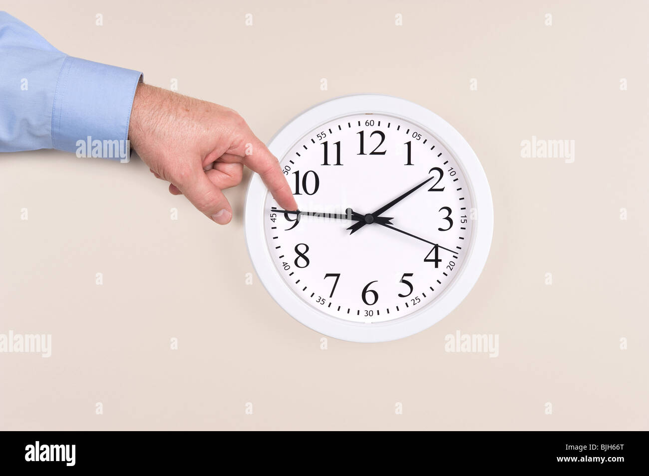 Un hombre usa su dedo para empujar la hora en un reloj al horario de verano Foto de stock