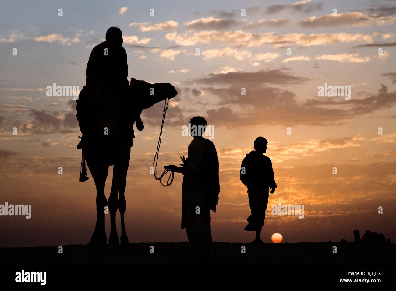 Hombres y camello. Parque Nacional de las dunas de arena de Sam. Desierto de Thar. Cerca de Jaisalmer. La India Foto de stock