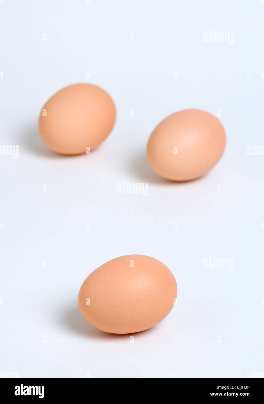 Alimentos crudos, huevos, tres huevos de rango libre sobre un fondo blanco. Foto de stock