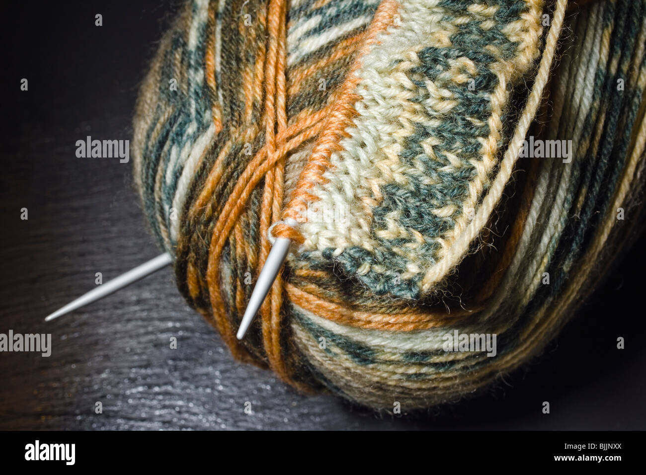 Tejer, bola de lana y agujas de tejer en un fondo de pizarra Foto de stock