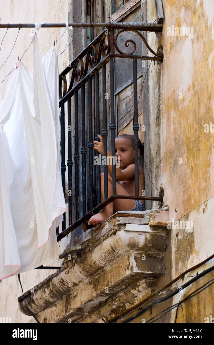 Joven cubano chico sentado en un balcón en La Habana. Foto de stock