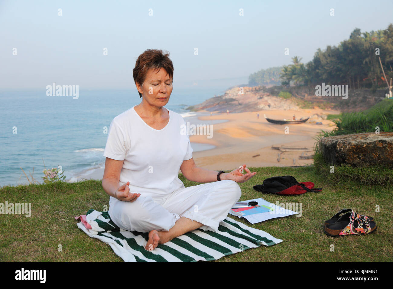 Mujer meditando sobre una pradera por encima del mar, Betsaida Ermita cerca de Kovalam, Kerala, India del Sur, India, Asia Foto de stock