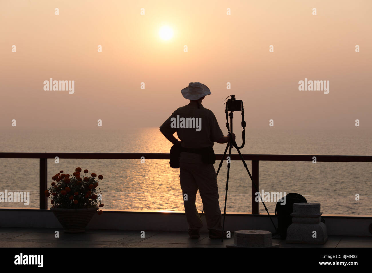 Fotógrafo con una cámara sobre un trípode en la parte frontal de la puesta de sol en el mar, Kovalam, Kerala, India del Sur, India, Asia Foto de stock