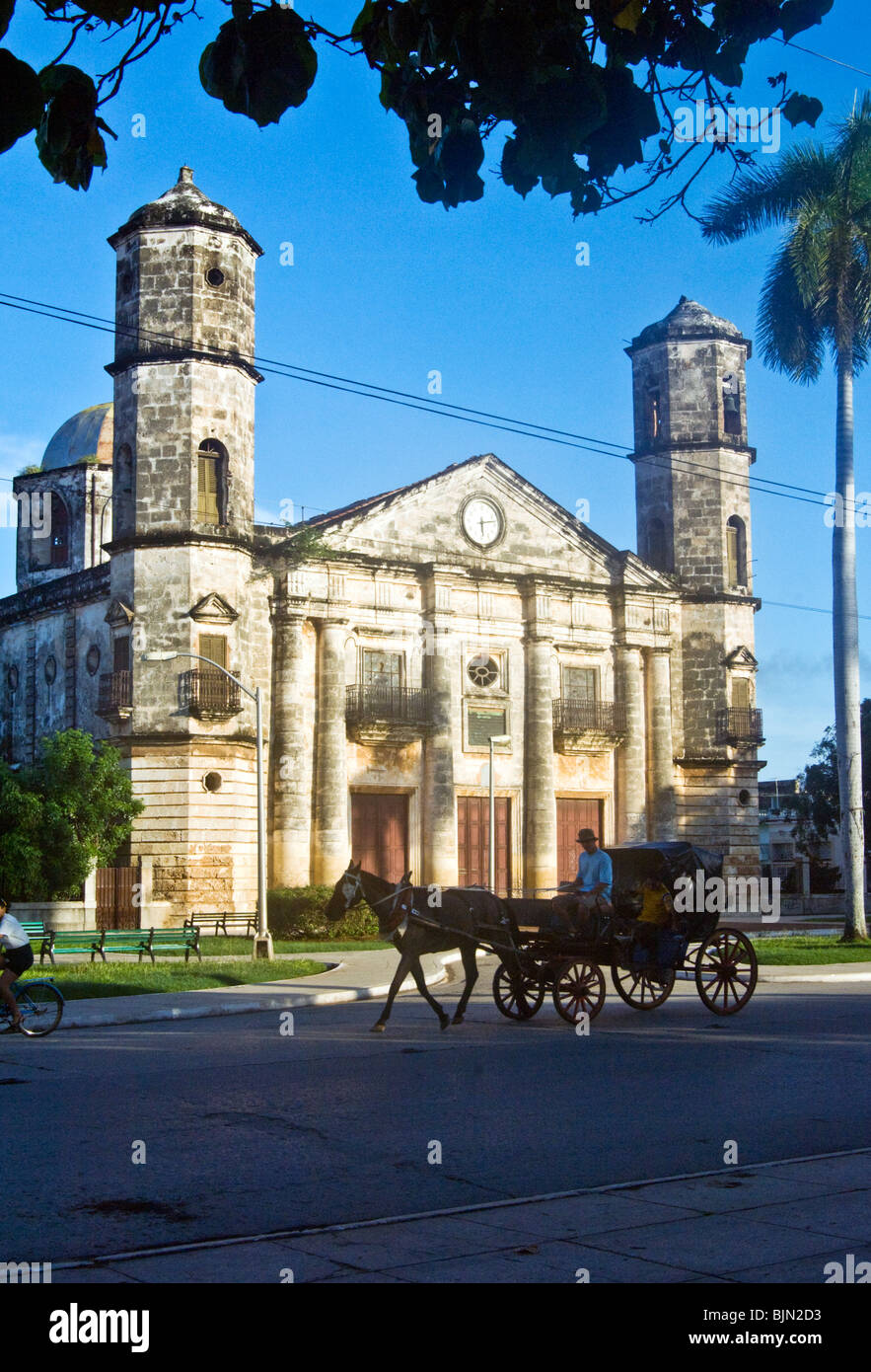 Caballo y carro taxi viajar pasado una iglesia en Cárdenas, Cuba Foto de stock