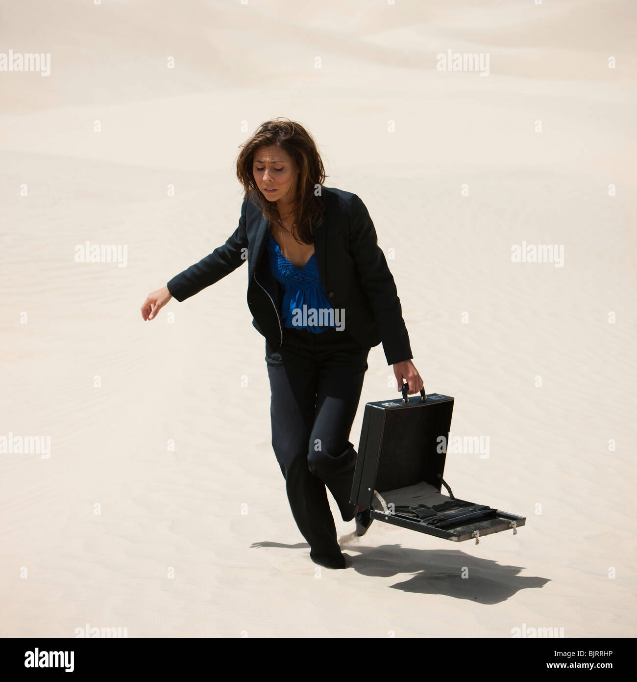 Estados Unidos, Utah, pequeño Sáhara, joven empresaria caminando en el desierto maletín de transporte Foto de stock