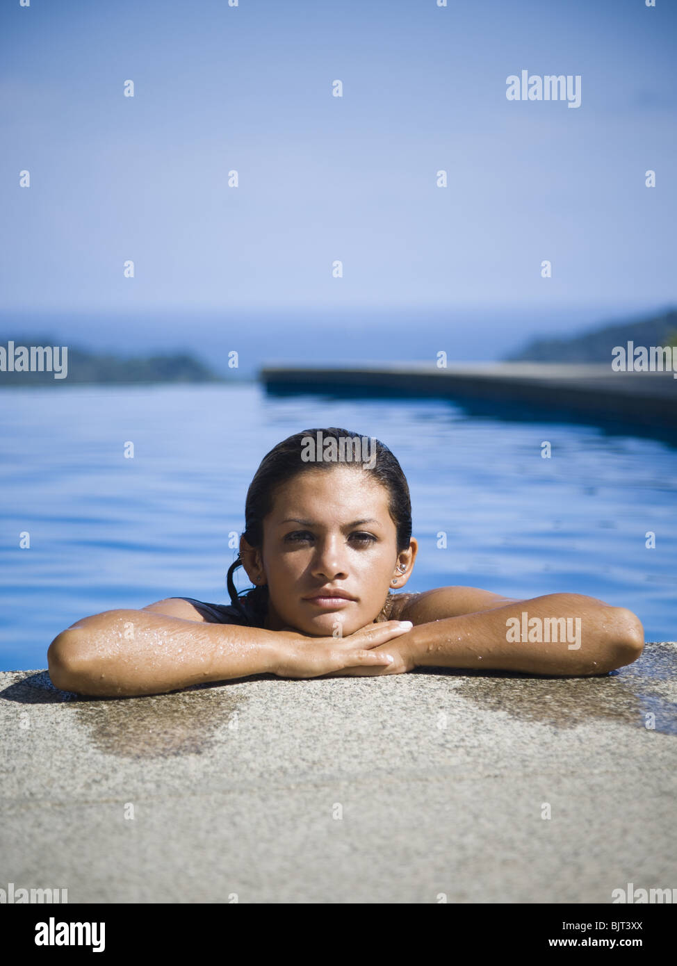 Mujer descansa sobre cornisa de piscina Foto de stock